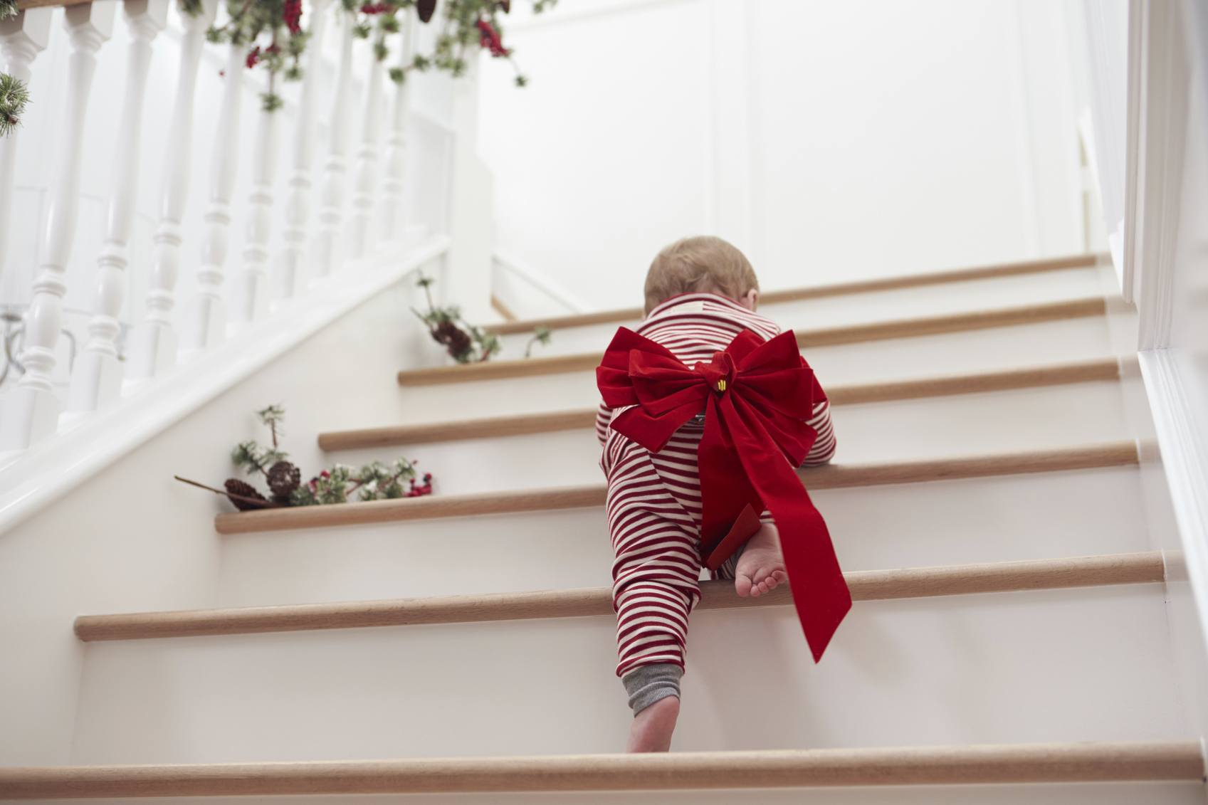 Baby crawling up staircase with bow